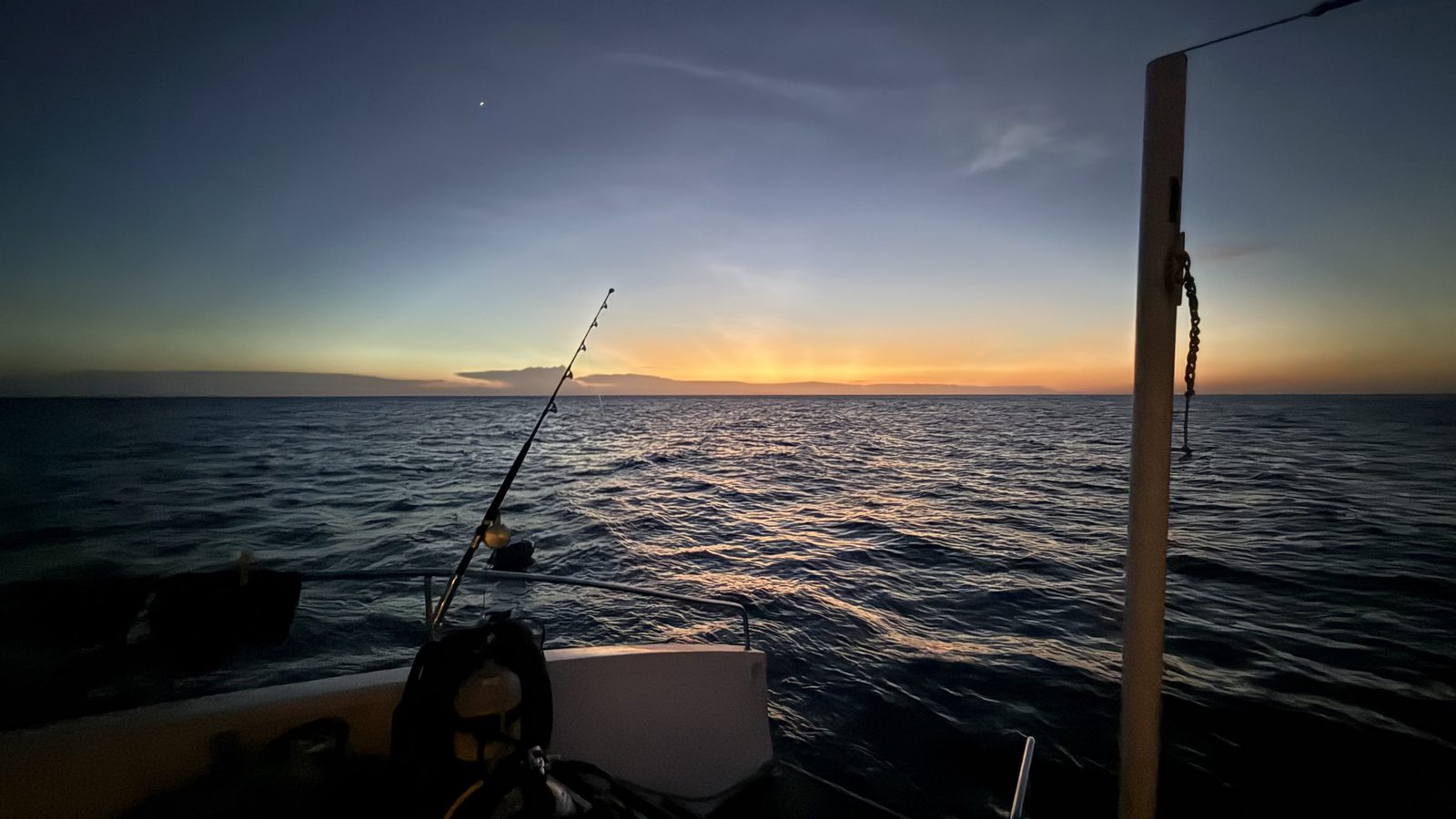 Sun rays bursting from behind a cloud over open water.